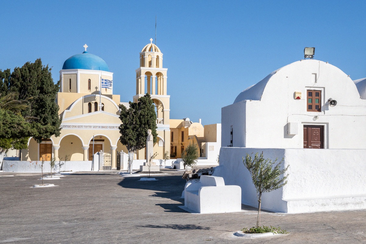 Weiße Kirche mit blauer Kuppel und Glockenturm in Oia auf Santorini